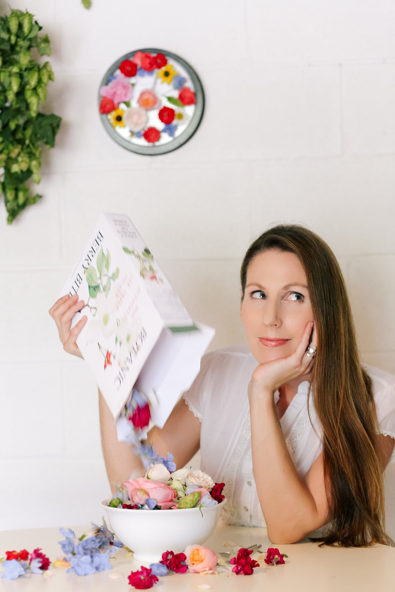 Business Owner  holding a cereal box filled and puring out with flowers into a bowl, set on a table with wall clock in the background