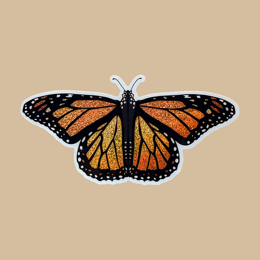 Butterfly-shaped sticker with orange, black, and yellow pattern on a beige background